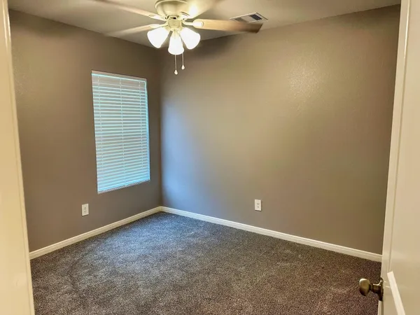 an empty room with windows and fan