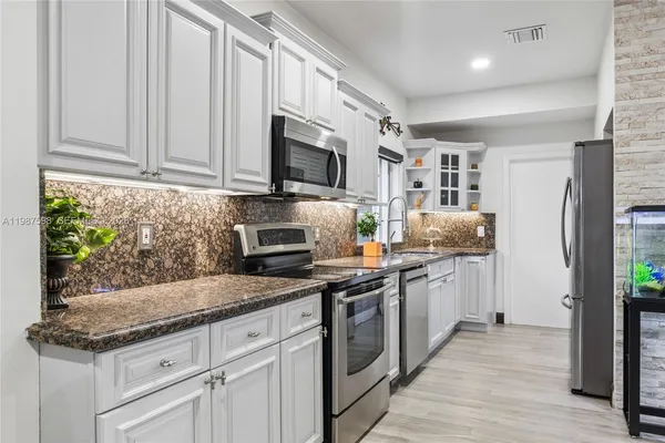 a kitchen with stainless steel appliances granite countertop a stove a sink and a microwave