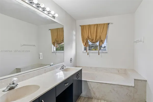 a bathroom with a double vanity sink a mirror and a bathtub