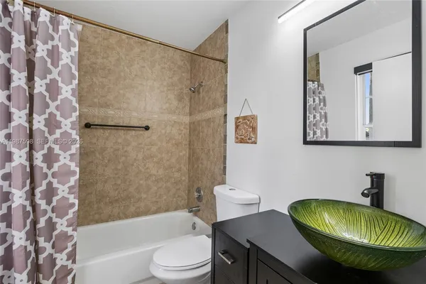 a bathroom with a sink a toilet a shower curtain and a bath tub