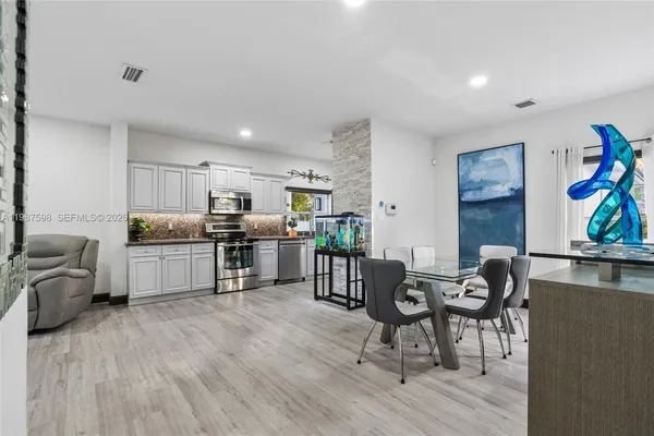 a living room with stainless steel appliances furniture and a wooden floor