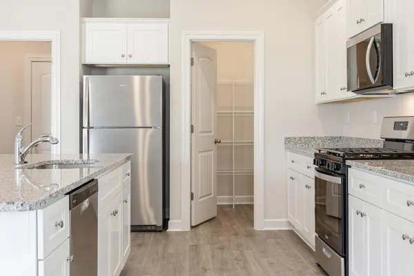 a kitchen with stainless steel appliances granite countertop a refrigerator a stove and a sink with wooden floor