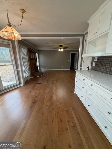 a view of a kitchen with a stove wooden cabinets and a floor to ceiling window