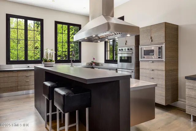 a living room with a white couches a dining table and a potted plant with wooden floor
