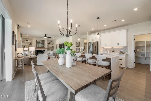 a view of a dining room and livingroom with furniture wooden floor kitchen chandelier