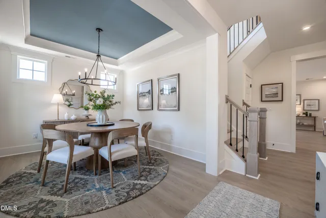 a dining room with wooden floor a chandelier a wooden table and chairs
