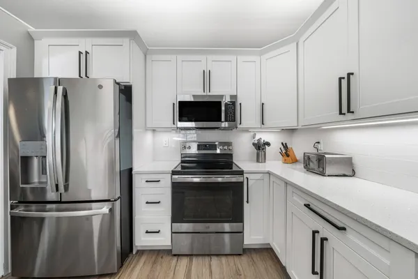 a kitchen with white cabinets and stainless steel appliances