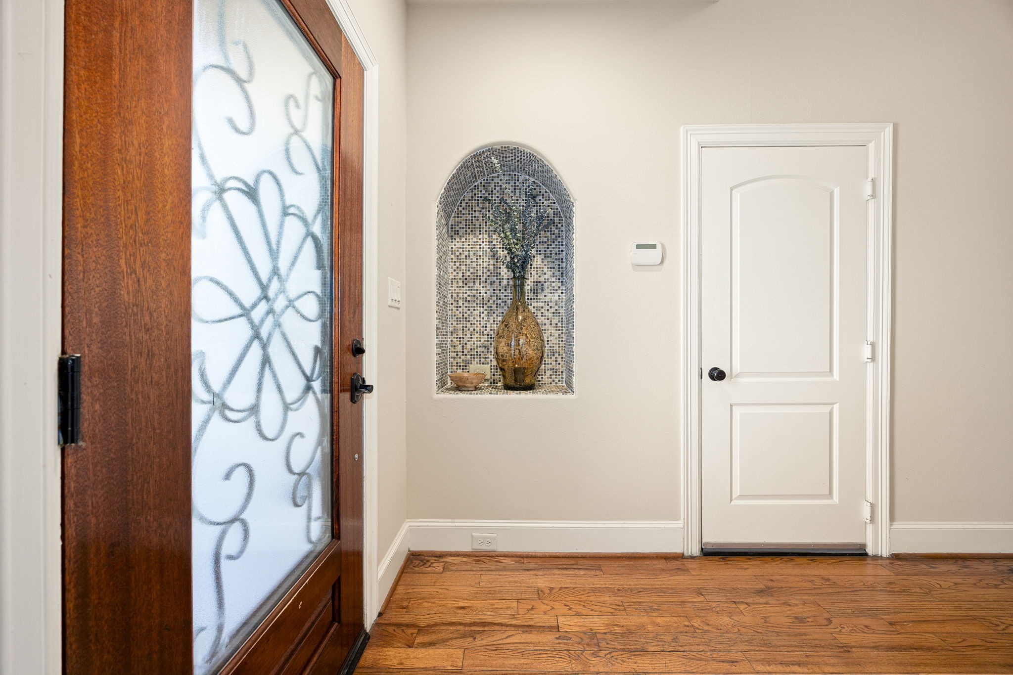 821 Lester Street Houston, TX 77007 - Photo 5 of 44 The entryway features a wooden door with decorative glass, hardwood flooring and a stylish recessed art niche with mosaic tile to portrait your most beautiful art or accessories.