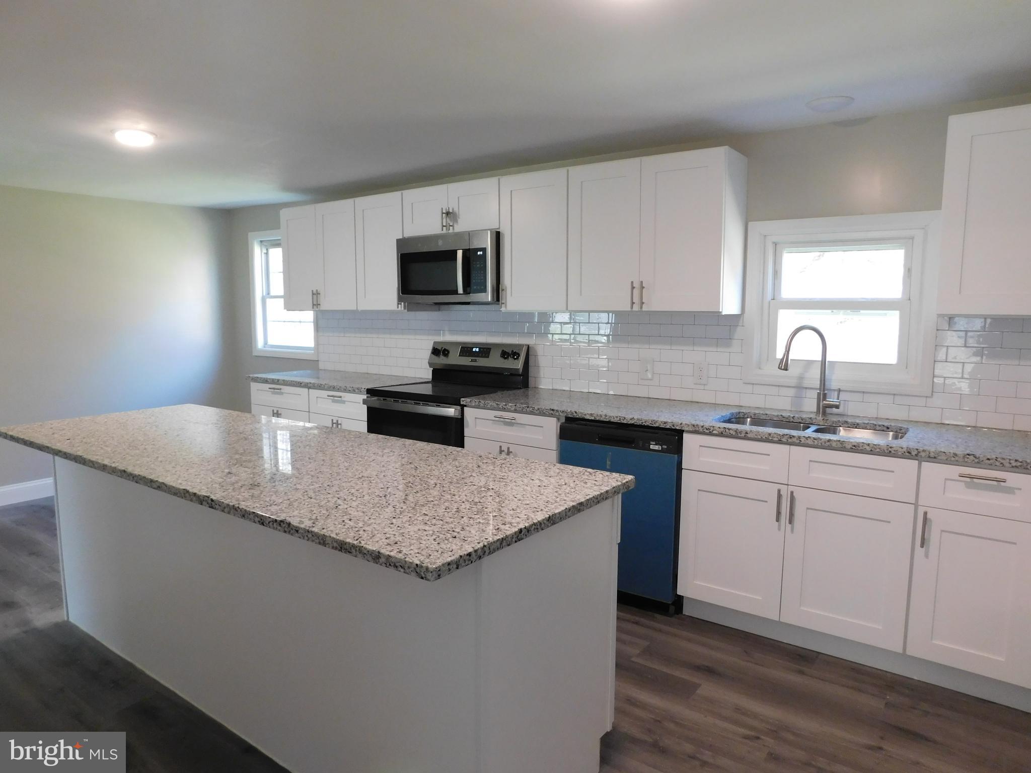 855 Shippy Road Manns Choice, PA 15550 - Photo 5 of 7 a kitchen with stainless steel appliances granite countertop a sink a stove a microwave a center island and a window