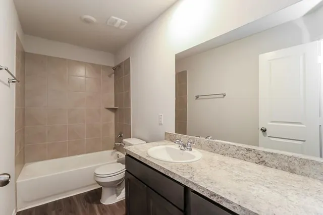 a bathroom with a granite countertop sink a toilet and bathtub