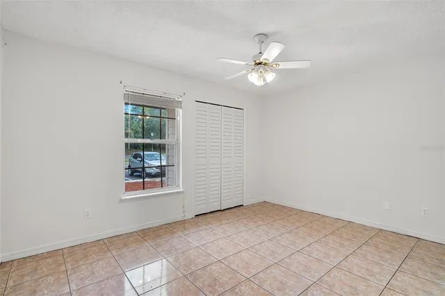 an empty room with windows and fan
