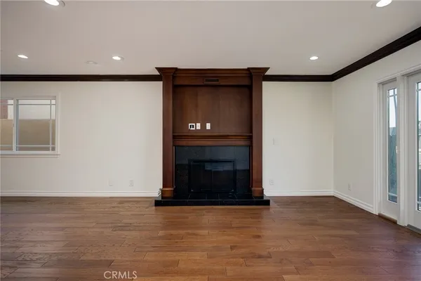 an empty room with wooden floor fireplace and windows