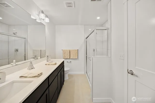 a spacious bathroom with a double vanity sink a mirror and shower
