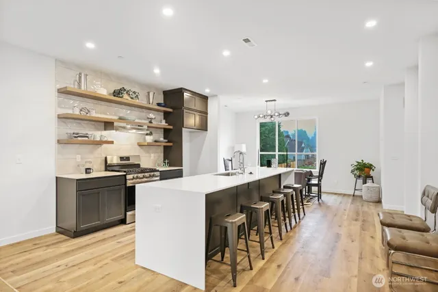 a kitchen with stainless steel appliances kitchen island granite countertop a stove and a dining table