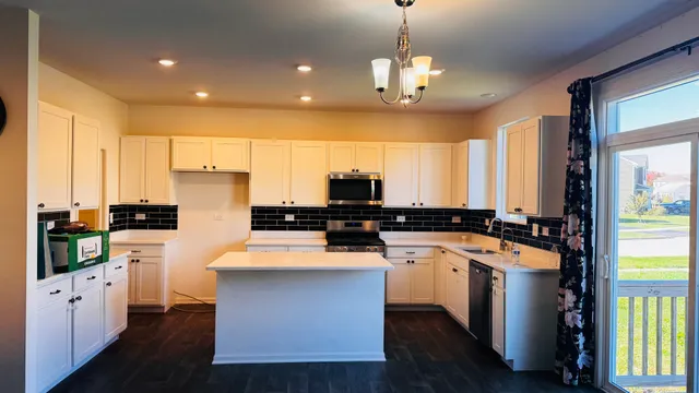 a kitchen with a center island wooden floor and stainless steel appliances