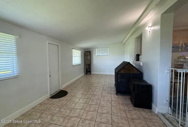 a living room with a black white checkered floor with a large mirror and a wooden floor