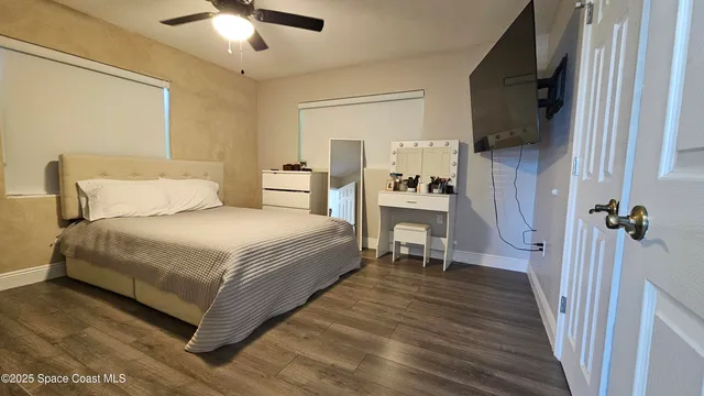 a bedroom with a bed a flat screen tv and a chandelier
