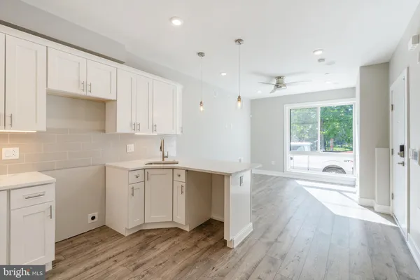 a kitchen with a hard wood floor white cabinets and stainless steel appliances