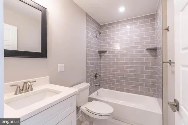 a bathroom with a bathtub shower sink mirror vanity and toilet