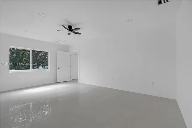 an empty room with a window and a ceiling fan