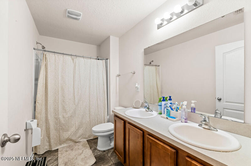 4076 Great Falls Loop Middleburg, FL 32068 - Photo 25 of 30 a bathroom with a granite countertop sink toilet and a mirror