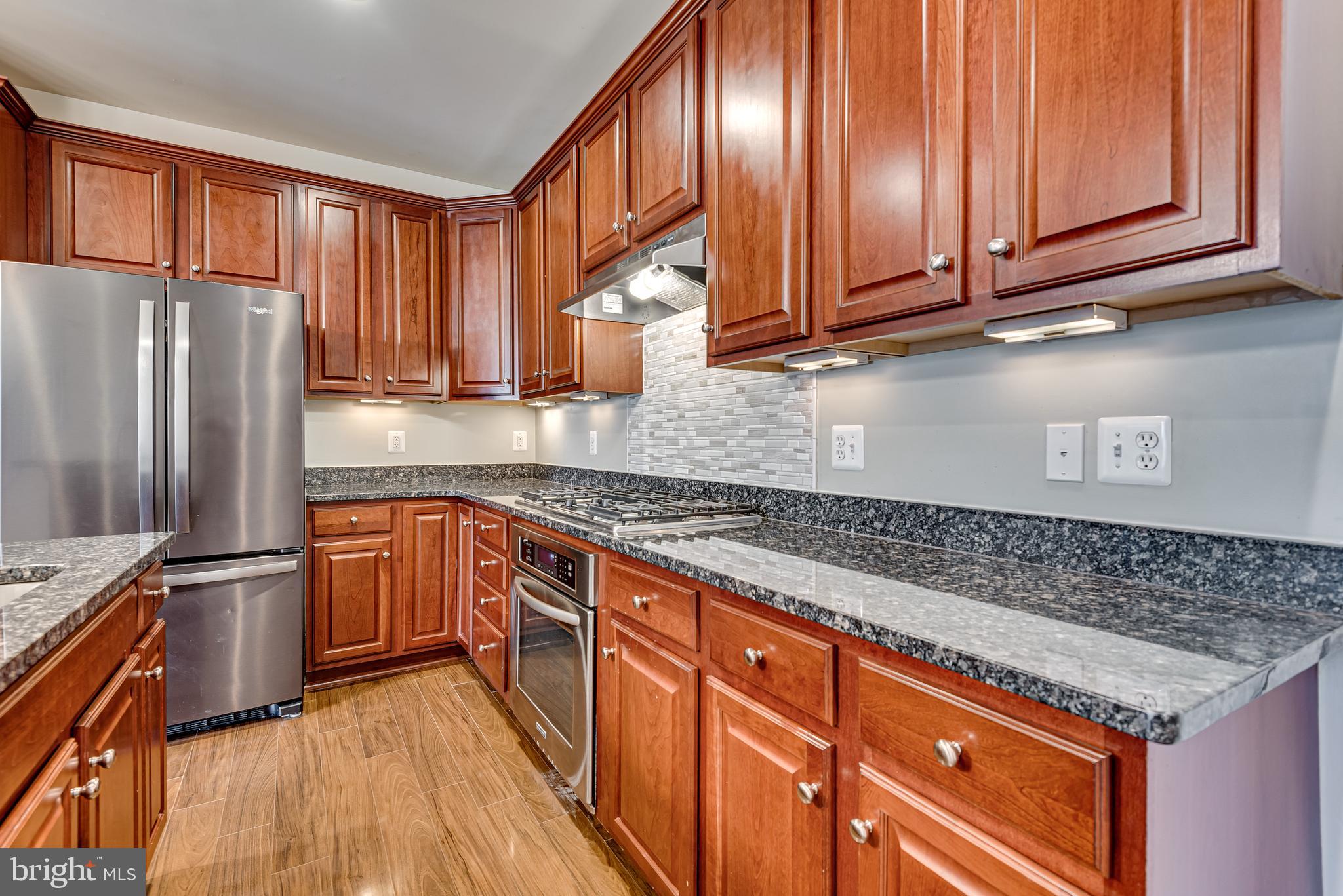 20654 Sibbald Square Ashburn, VA 20147 - Photo 15 of 43 a kitchen with stainless steel appliances granite countertop a stove a sink dishwasher and wooden cabinets with a granite countertops