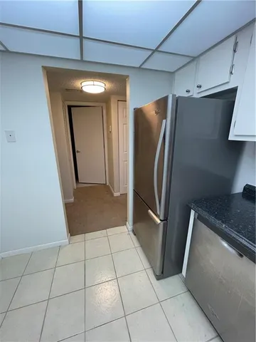 a view of a refrigerator in kitchen and an empty room