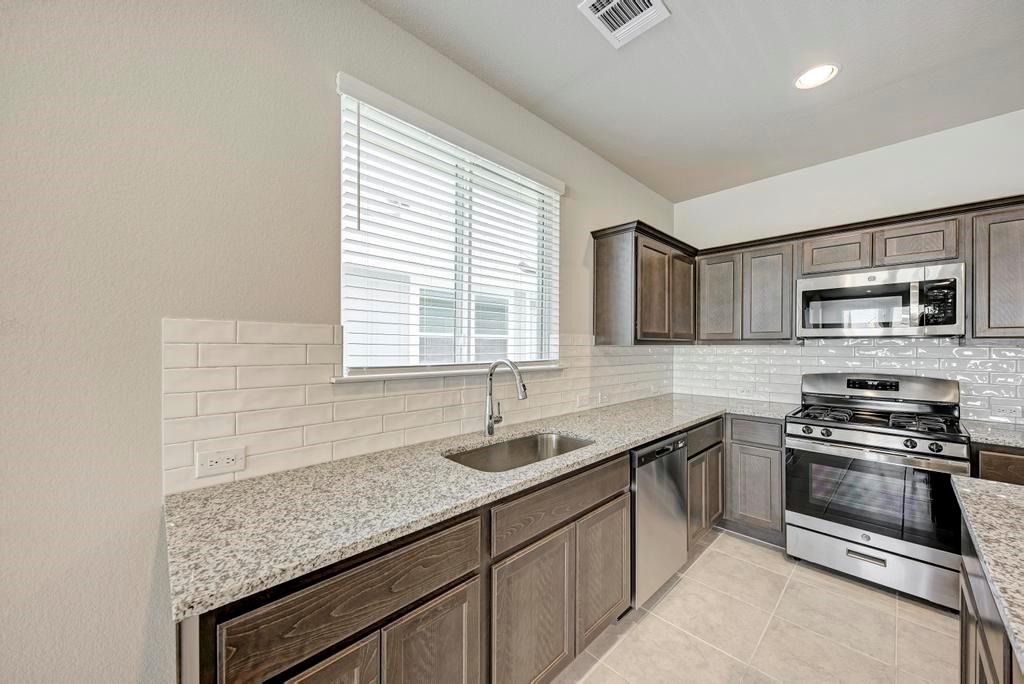 1209 Goforth Road Kyle, TX 78640 - Photo 9 of 32 Culinary creations come to life in this modern kitchen with stainless steel appliances and ample counter space.