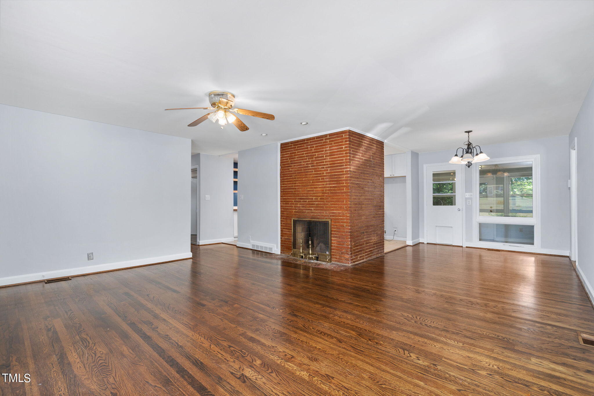 126 Clarendon Crescent Raleigh, NC 27610 - Photo 16 of 40 an empty room with wooden floor chandelier fan and windows