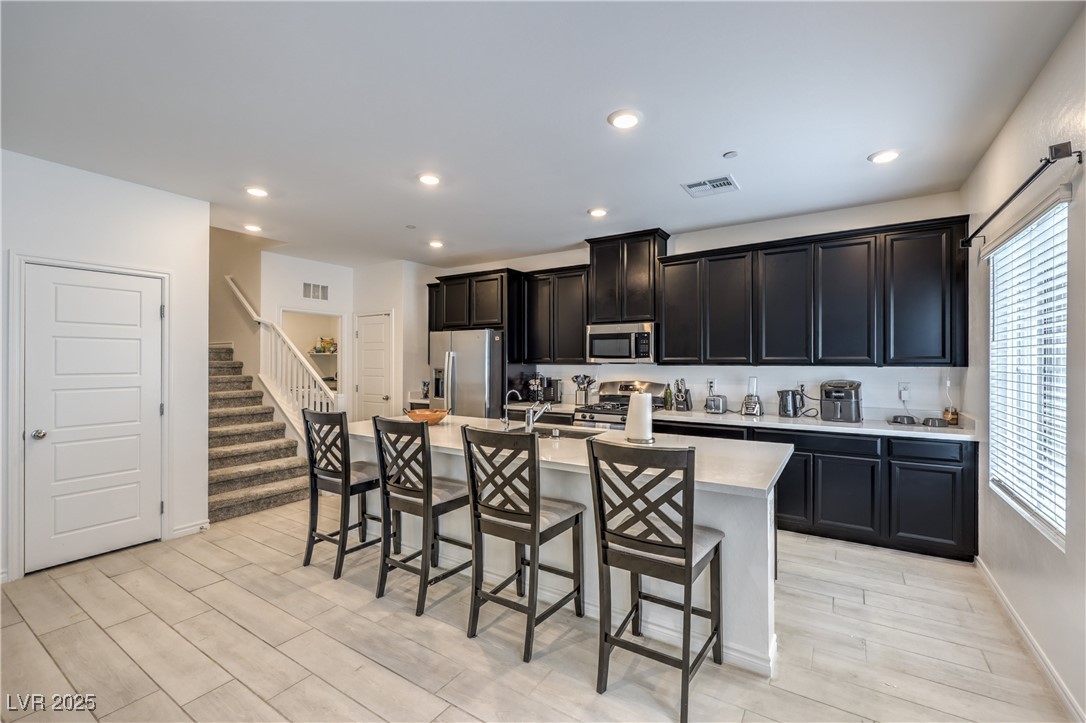 7232 North Decatur Boulevard, Unit 4 North Las Vegas, NV 89084 - Photo 11 of 36 Kitchen with a breakfast bar area, stainless steel appliances, visible vents, light countertops, and a center island with sink