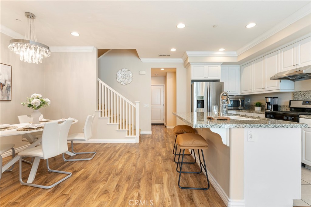 869 East Mountain Way, Unit D Azusa, CA 91702 - Photo 13 of 55 a kitchen with stainless steel appliances granite countertop a stove top oven a sink dishwasher and white cabinets with wooden floor