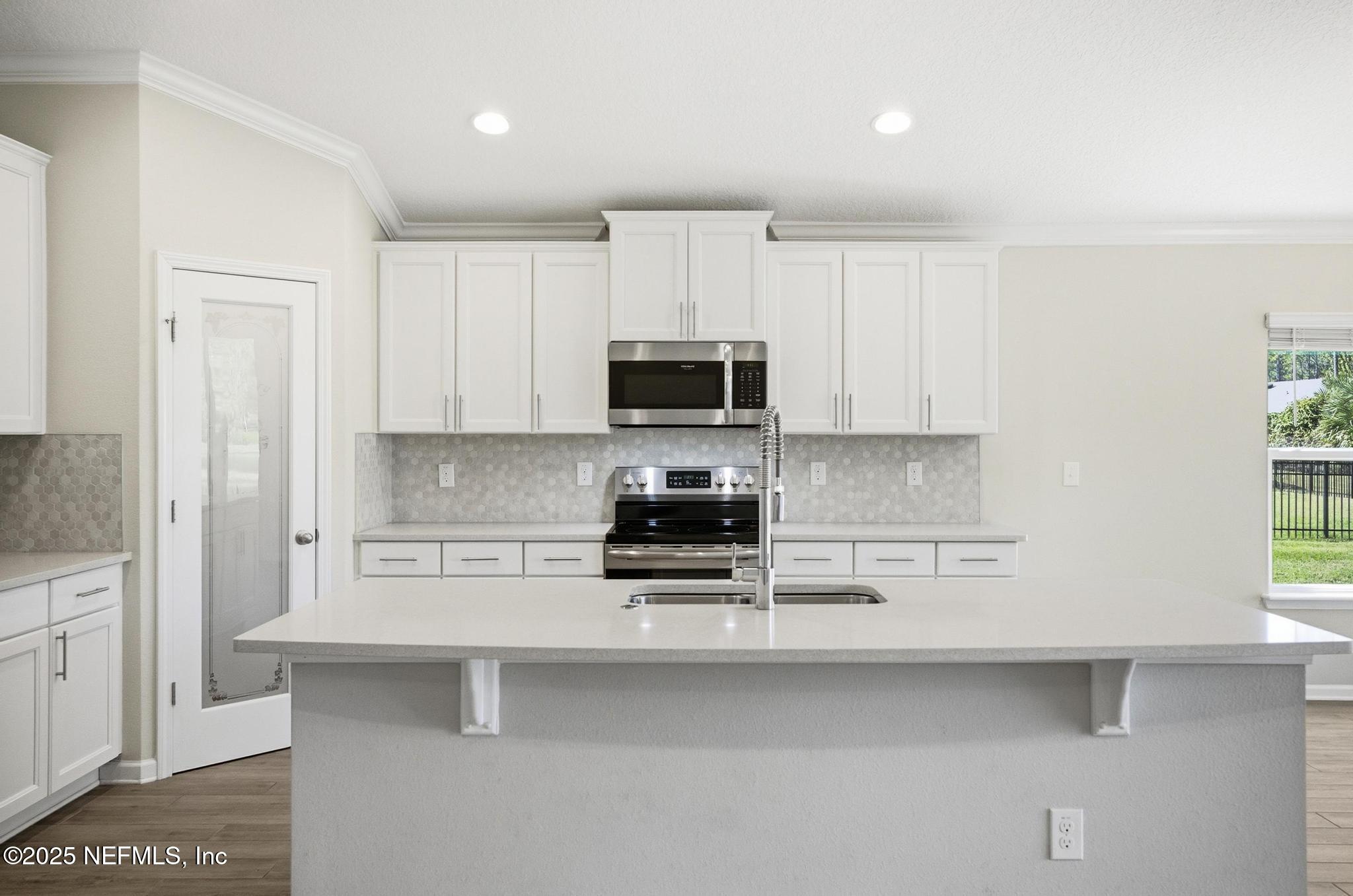83 Hummingbird Court Palm Coast, FL 32164 - Photo 10 of 70 a kitchen with stainless steel appliances a stove a microwave and white cabinets