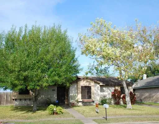 a front view of a house with a yard and large tree