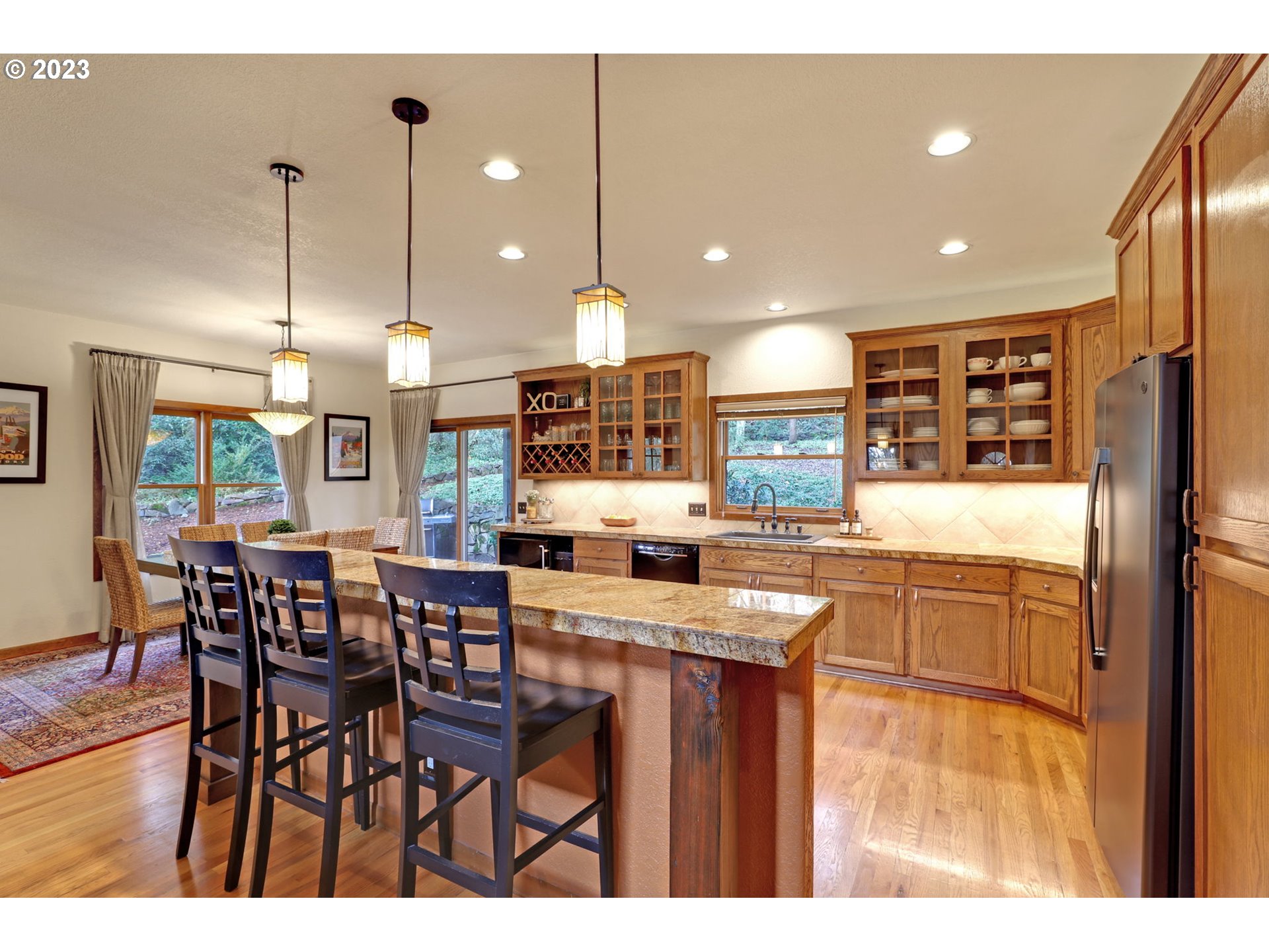 12434 Southwest 57th Avenue Portland, OR 97219 - Photo 10 of 34 a kitchen with stainless steel appliances kitchen island granite countertop a table chairs and a refrigerator