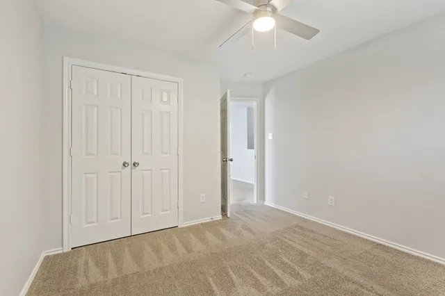 an empty room with a ceiling fan and carpet