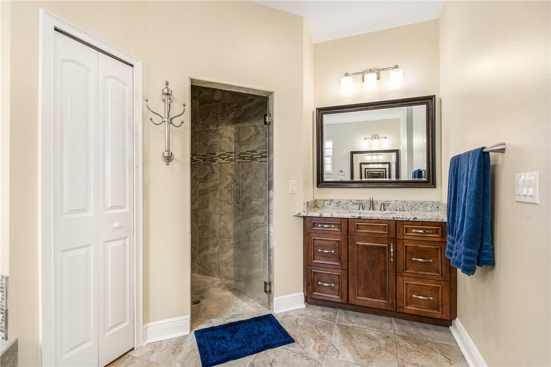 7635 Agawam Road Micco, FL 32976 - Photo 23 of 36 a bathroom with a granite countertop sink a mirror and a shower
