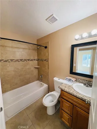 a bathroom with a granite countertop sink a toilet a mirror and shower