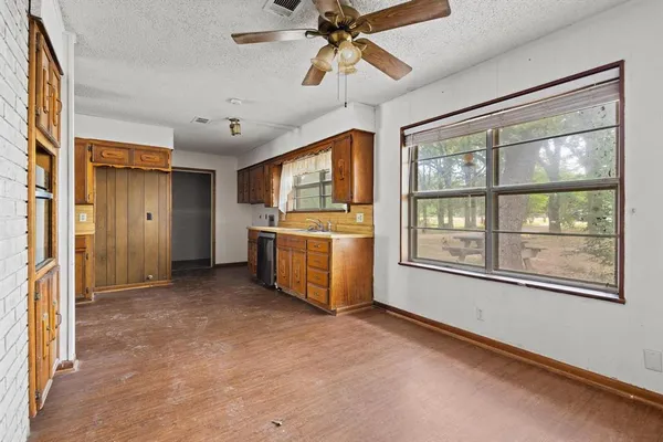 a view of a kitchen with a stove cabinets a ceiling fan and wooden floor