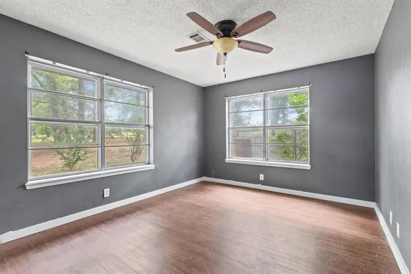 an empty room with a window and a ceiling fan