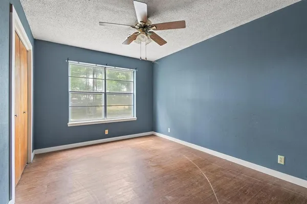 an empty room with a window and a fan