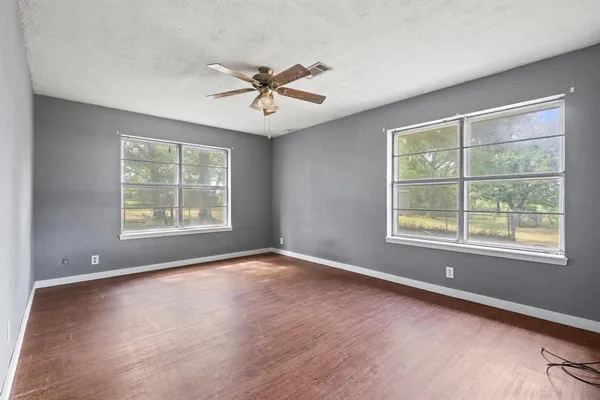 a view of an empty room with a window and wooden floor