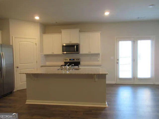 a view of a kitchen with kitchen island a sink wooden floor and a refrigerator