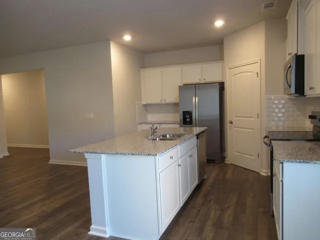 a kitchen with a sink a refrigerator and wooden floor