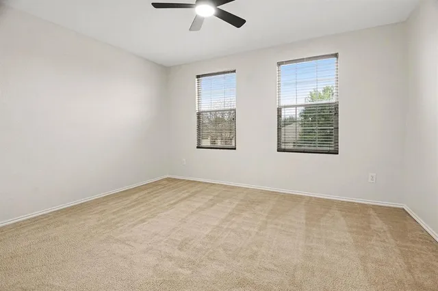 an empty room with windows and fan