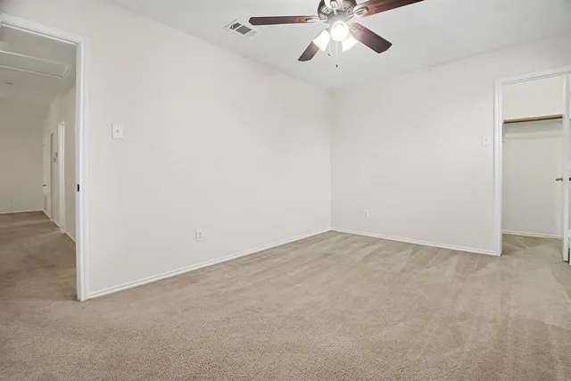 a view of an empty room with a chandelier fan