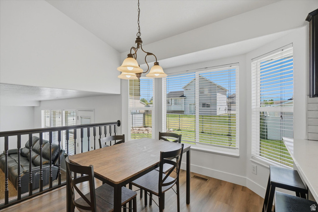 5576 South 4100th Street West Roy, UT 84067 - Photo 12 of 35 Bright dining area featuring a bay window, LVP flooring, and an open railing overlooking a lower level