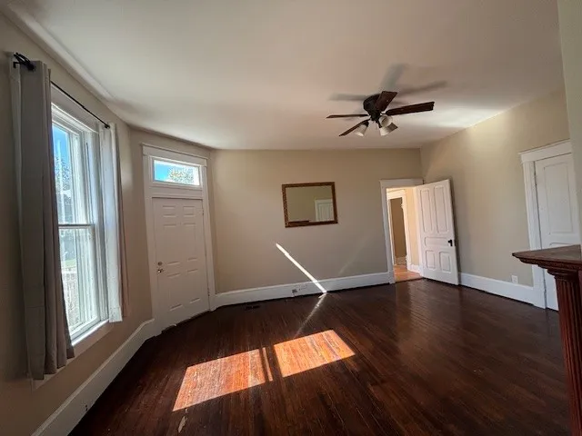 a view of an empty room with a window and wooden floor