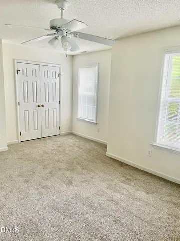 an empty room with windows and fan