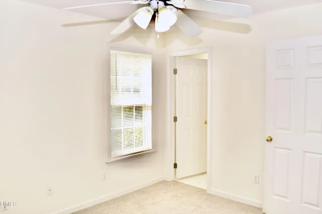 an empty room with a windows and chandelier fan