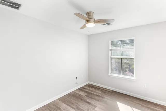 an empty room with a window and ceiling fan